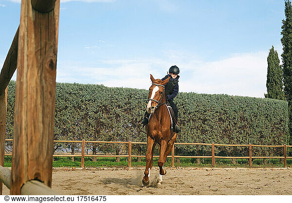 Young boy horseback riding trot at ranch.
