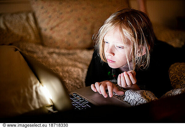 Young boy in bed using laptop computer