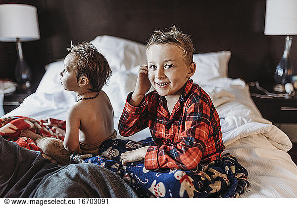 Young boy in pajamas sitting on hotel bed on vacation