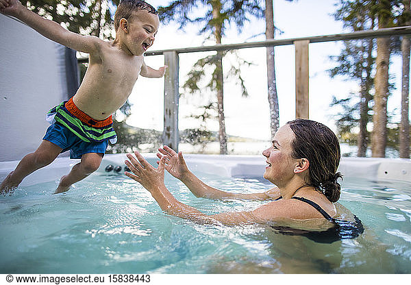 Young boy jumping into swimming pool  mom waiting to catch him.