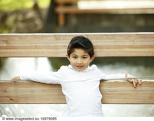 Young boy looking at camera while on park bridge
