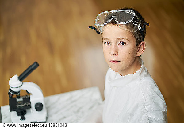 young boy looks at camera dressed in white coat prepares to observe by