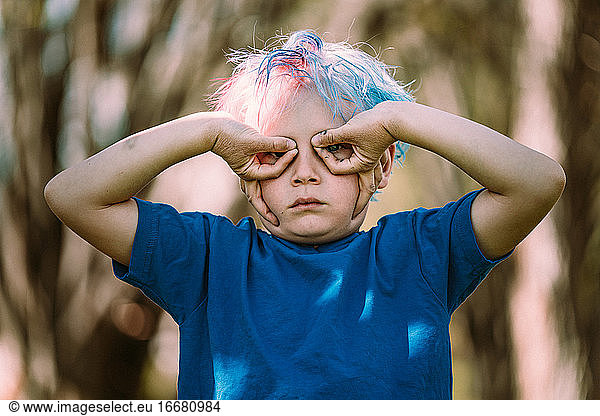 Young boy making upside down hand glasses