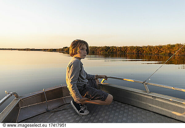 Young boy on a boat on the waters of the Okavango Delta at sunset  Botswana.