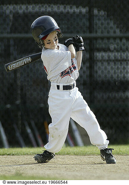 Young boy playing baseball in uniform.