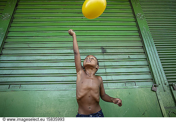 Young boy playing in the streets with BrazilianÂ´s flag colors elements
