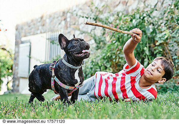 Young boy playing with his dog  french bulldog  in the garden