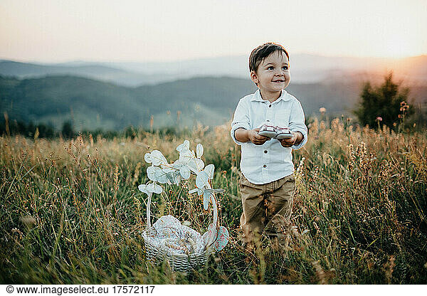 Young boy playing with his sister's shoes in the nature