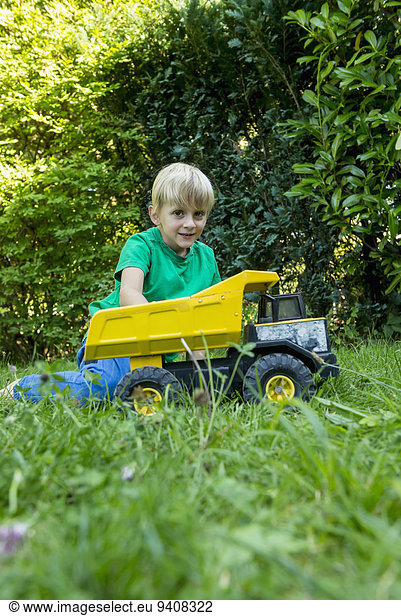 Young boy playing with toy car in the garden