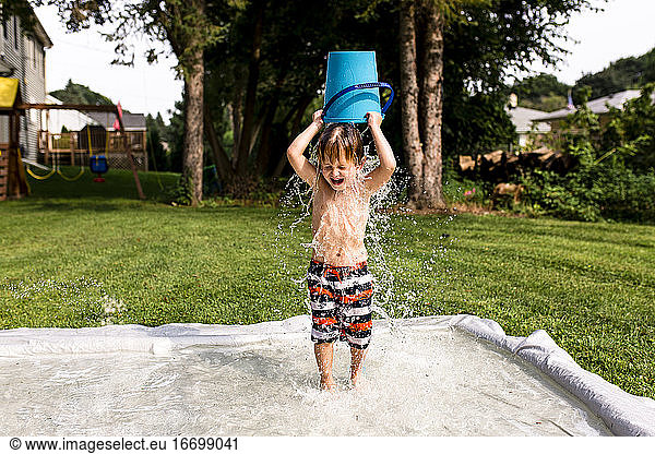 Young Boy Pouring Water Bucket Over Head