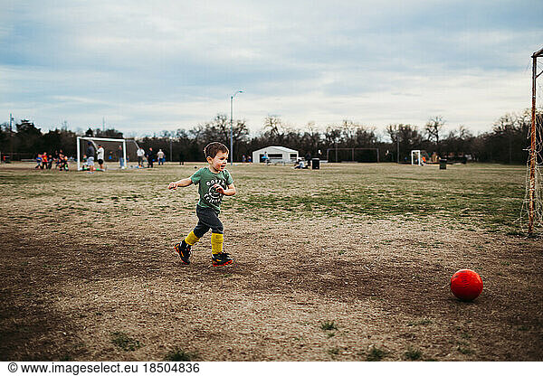 Young boy running towards soccer ball outside