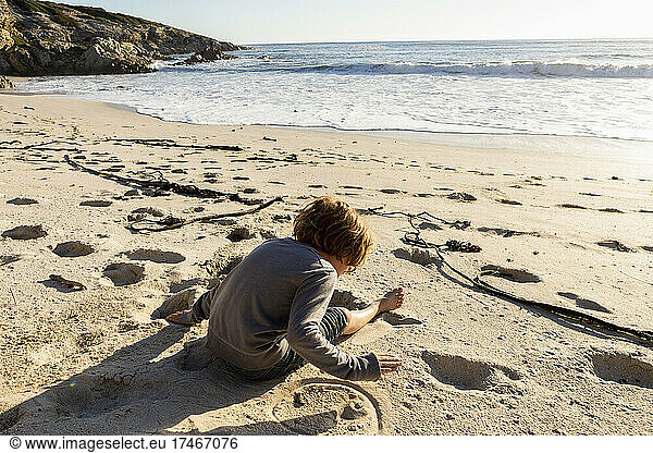 Young boy sitting on a sandy beach