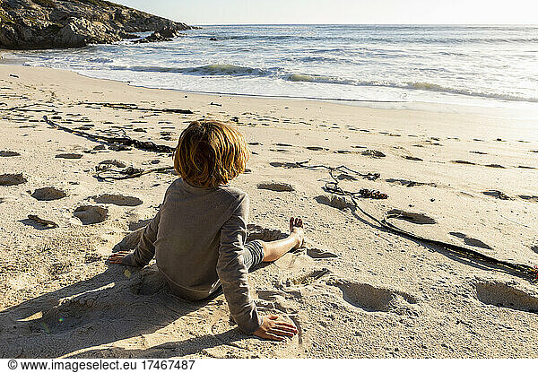 Young boy sitting on a sandy beach