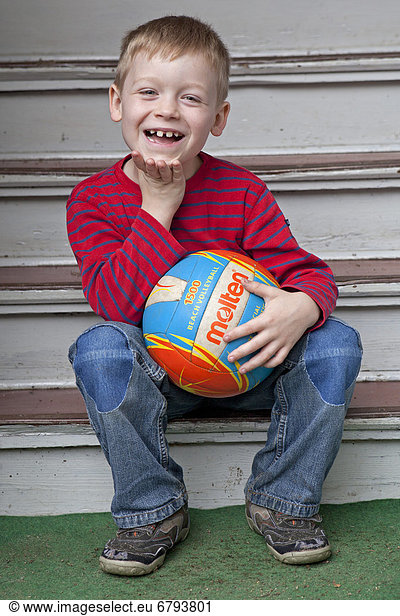 Young boy sitting on stairs with a ball