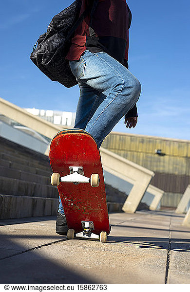 Young boy skateboarding in a city park in sunny day  low angle view