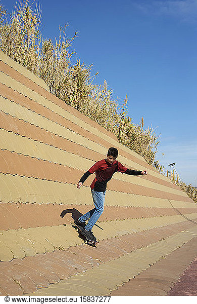 Young boy skateboarding on ramp in a city park in sunny day
