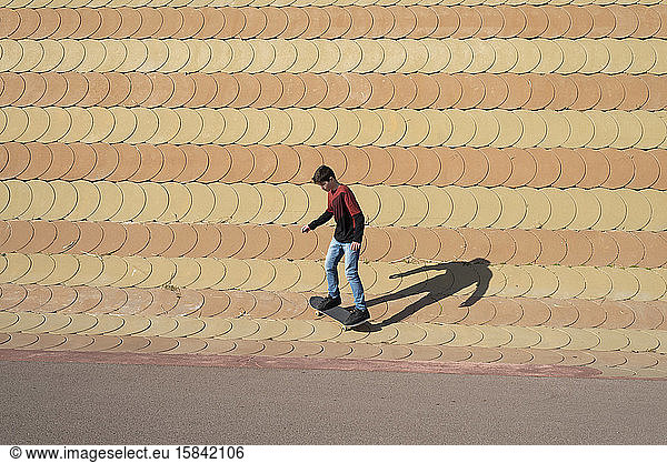 Young boy skateboarding on ramp in a city park in sunny day