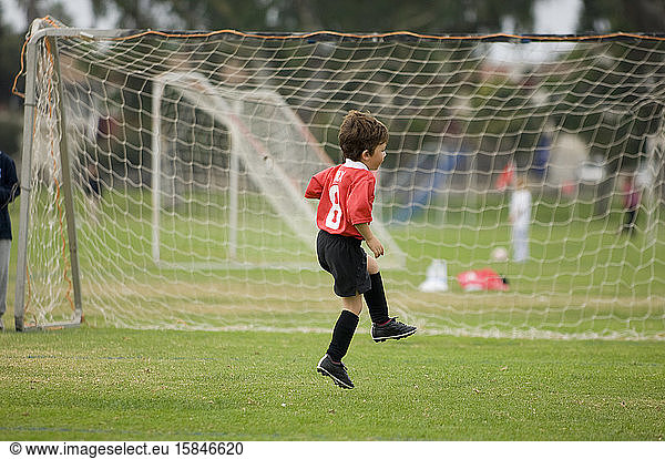 Young boy skipping in front of goal on a soccer field