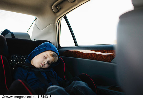 Young boy sleeping in back seat of car
