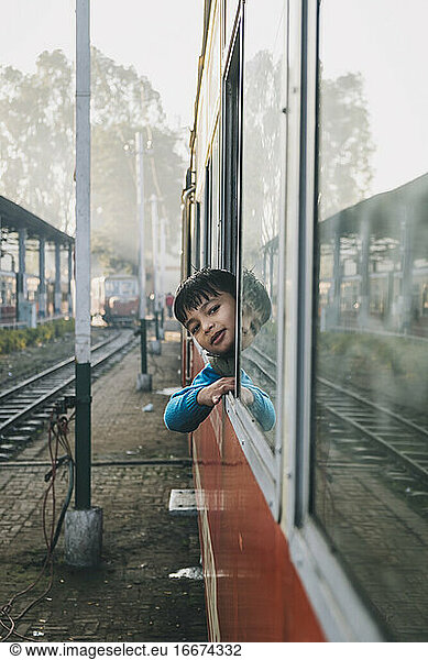 Young boy smiling through Toy Train window at Kalka Station  Haryana  India