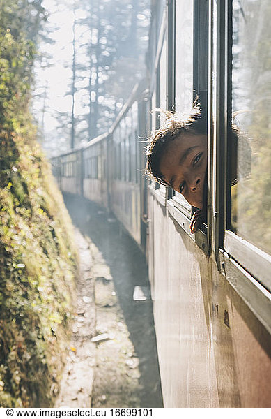 Young boy smiling through Toy Train window  while train goes up from Kalka to Shimla