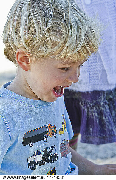 Young Boy Smiling While Playing In Sandbox.