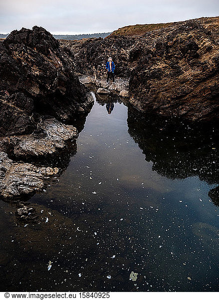 Young Boy standing by large tide pool on the coast of California