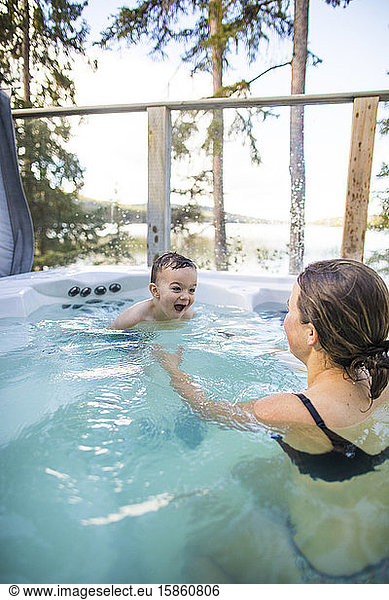 young boy swimming o mother in hot tub during vacation.