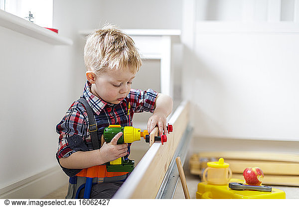 Young boy using toy power tool at home