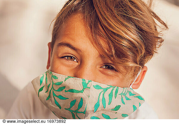Young boy wearing a mask and looking at camera.