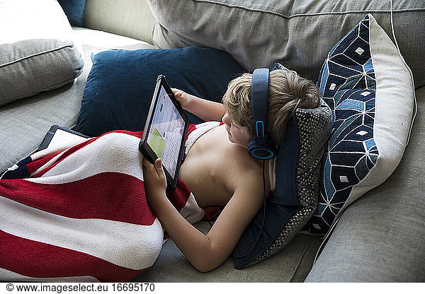 Young Boy Wearing Headphones Does Virtual School on Tablet Computer