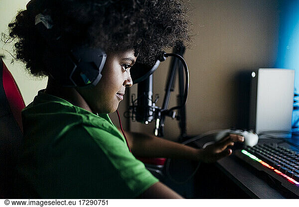 Young boy wearing headphones playing video game at home