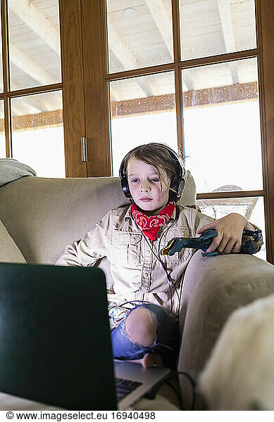 Young boy wearing safari outfit and headphones watching a movie on laptop