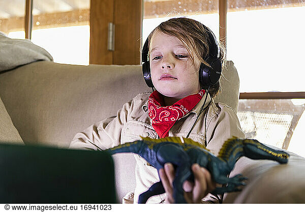 Young boy wearing safari outfit and headphones watching a movie on laptop