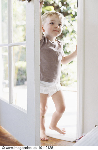 Young boy wearing T-Shirt and pants  opening a door.