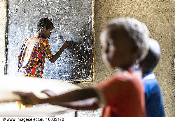 Young boy writing on blackboard at school  Melabday  Asso Bhole  Danakil Depression  Afar Region  Ethiopia  Africa