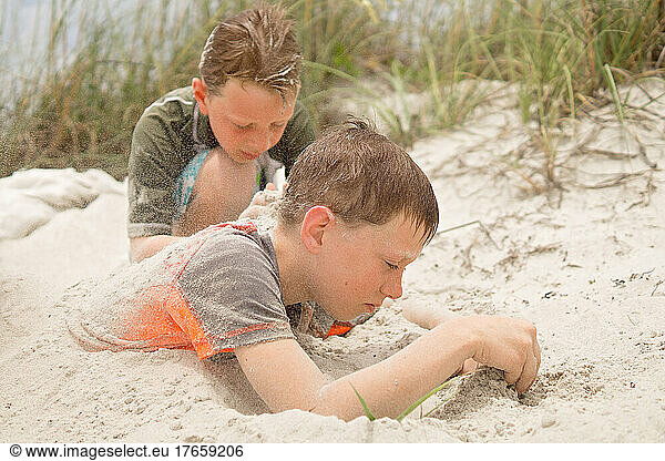 Young boys playing in the sand near sea grass