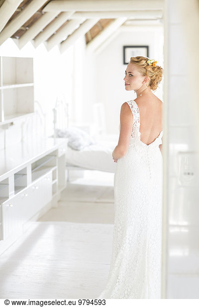 Young bride standing in sunny bedroom