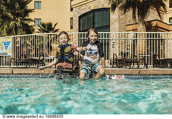 Young brothers jumping into pool together on vacation in Palm Springs