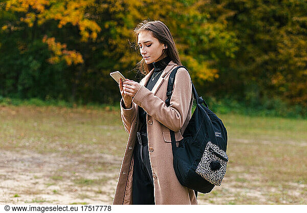 Young brunette girl holding smartphone and checking message