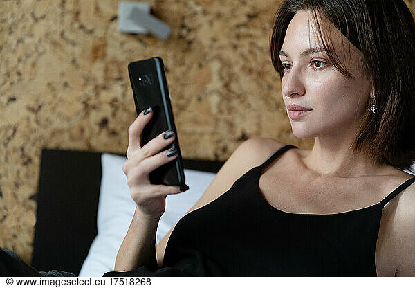 Young brunette woman looking at phone at home