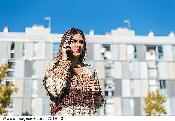 Young brunette woman talking on cell phone. Autumn outfit.