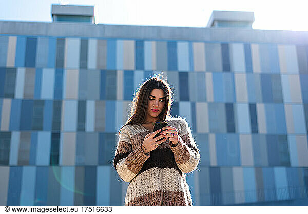 Young brunette woman using her mobile phone in the city.