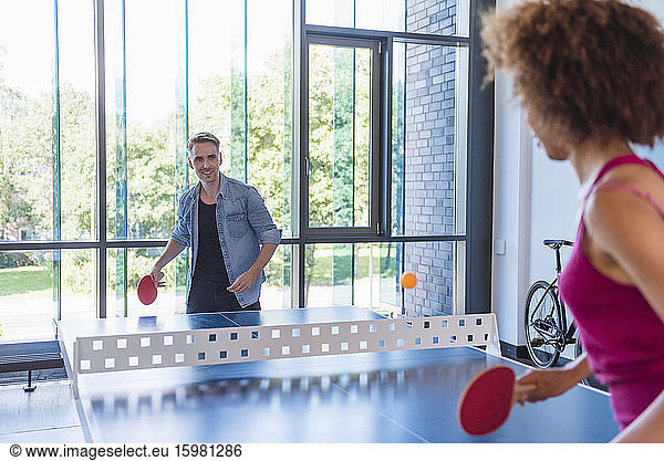 Young business people plaing table tennis in loft office