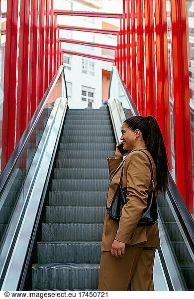 Young business woman talking on her cellphone on an escalator