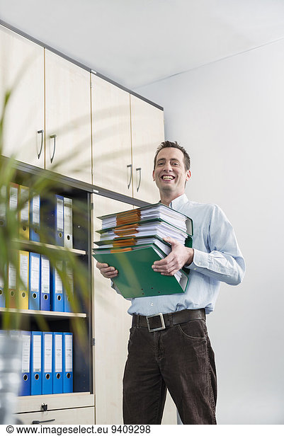 Young businessman carrying pile filing folders