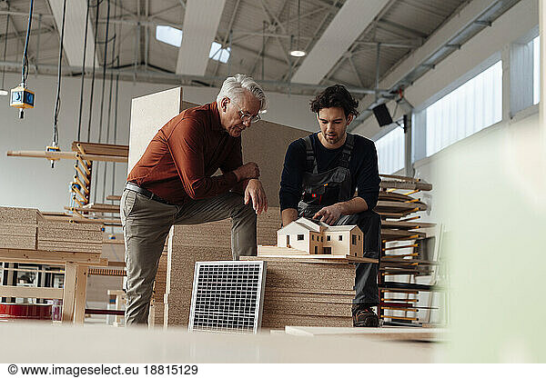 Young businessman discussing over model house in industry