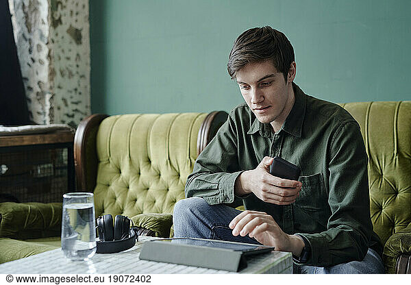 Young businessman sitting at table in modern cafe using tablet PC