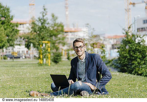 Young businessman sitting in park  using laptop
