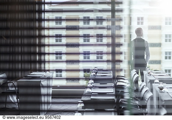 Young businessman standing in conference room looking out of window